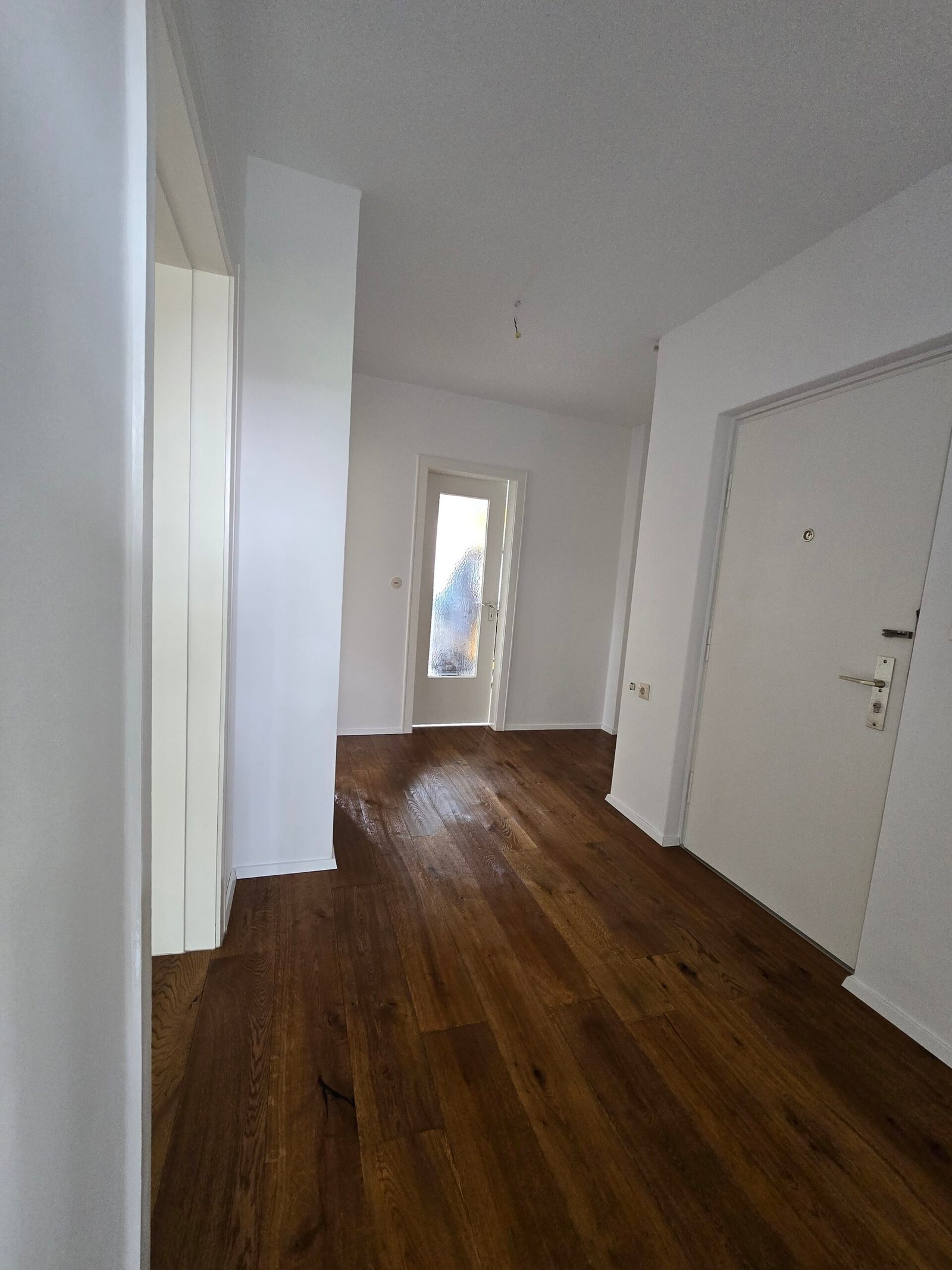 Modernisierter Eingangsbereich mit Parkett und weißen Wandflächen