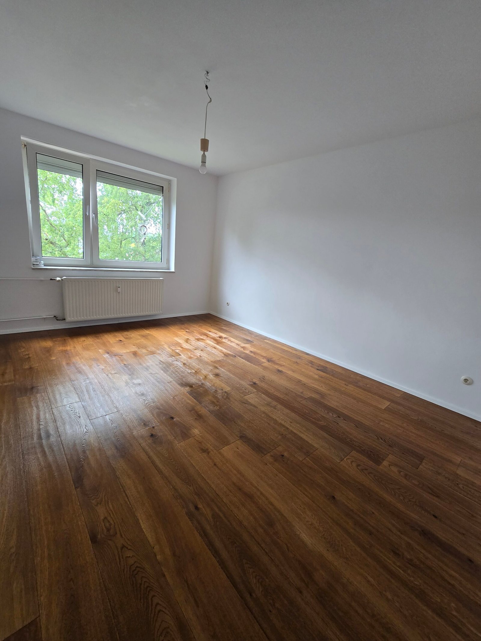 Modernisierter Wohnraum mit weißen Wänden und neuem Parkett