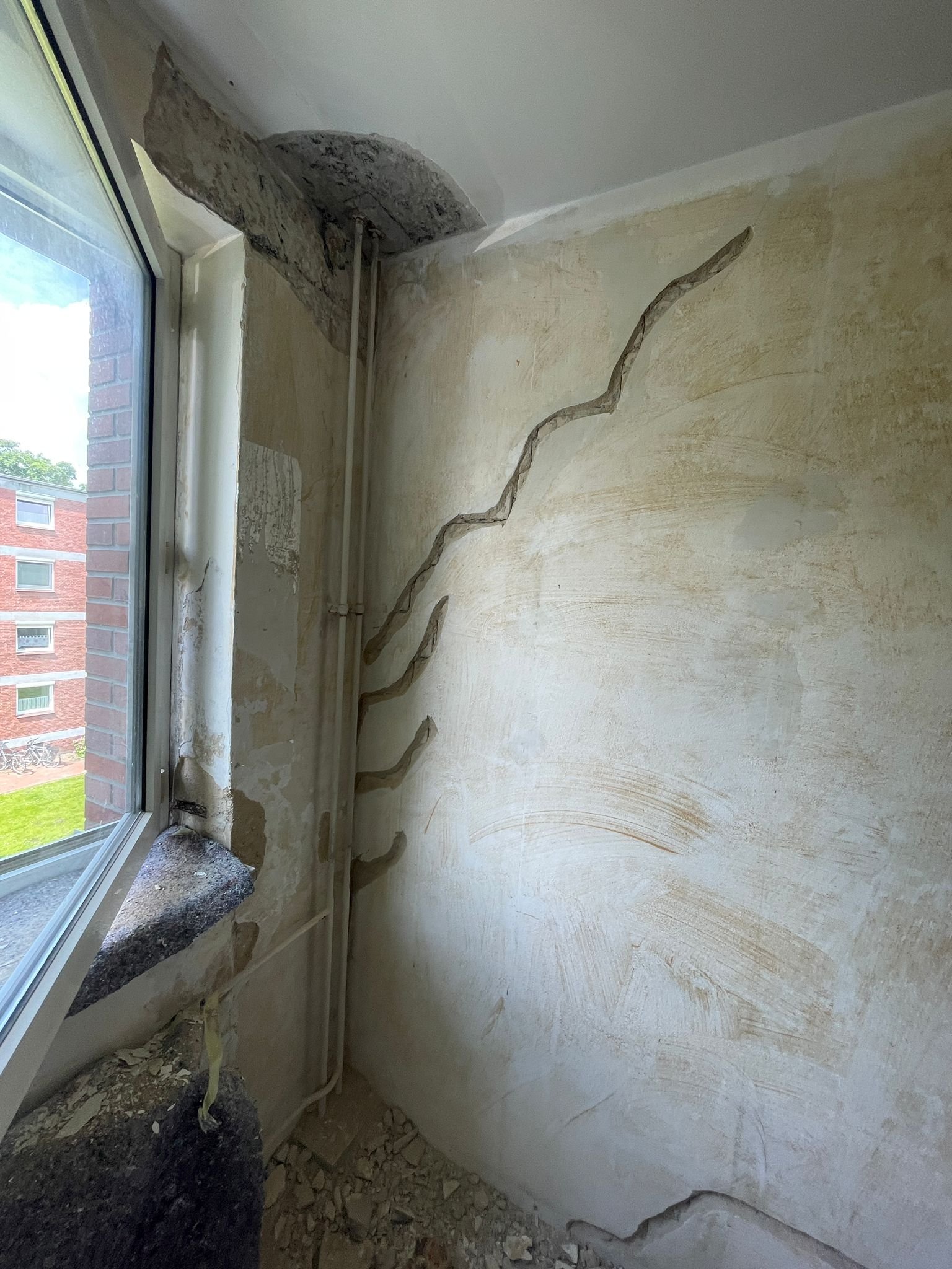 Bearbeitete Risse in der Wandfläche neben dem Fenster